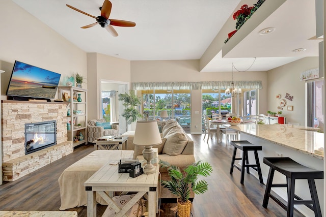 living room with dark wood-type flooring, a stone fireplace, and a healthy amount of sunlight