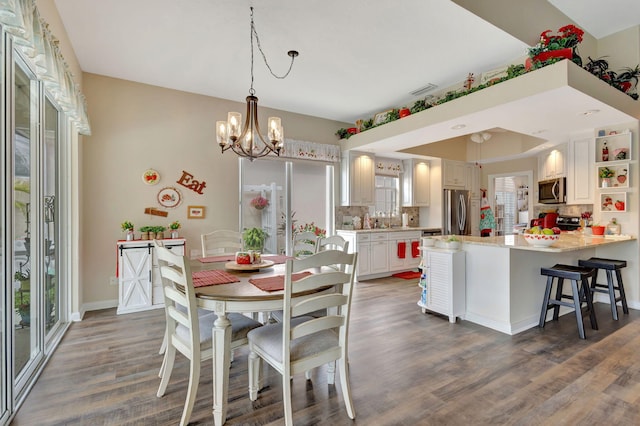 dining room featuring sink, an inviting chandelier, and dark hardwood / wood-style flooring