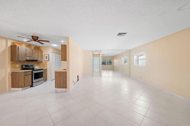 kitchen with stainless steel range with electric stovetop, backsplash, ceiling fan, light tile patterned floors, and a textured ceiling