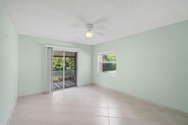 tiled empty room with ceiling fan and a textured ceiling