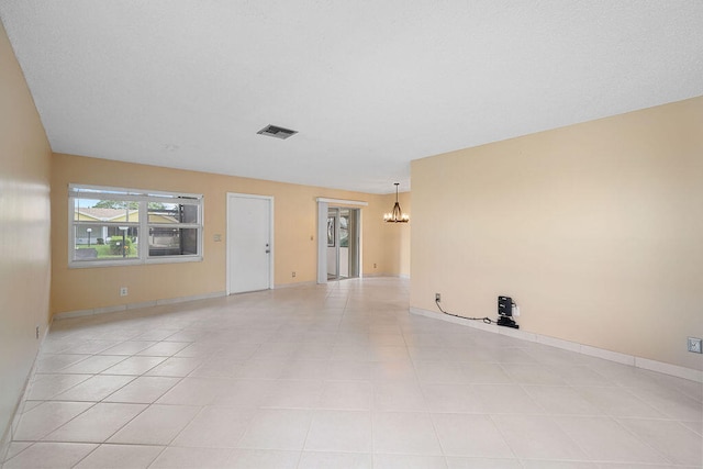 empty room with an inviting chandelier and light tile patterned flooring