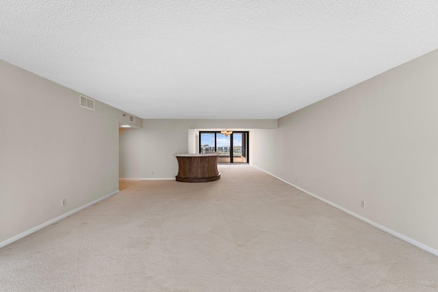 unfurnished living room with light carpet and a textured ceiling