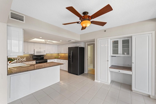 kitchen featuring kitchen peninsula, backsplash, black appliances, light tile patterned floors, and white cabinetry