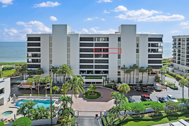 view of building exterior featuring a community pool and a water view