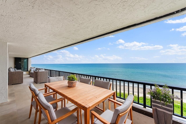 balcony featuring outdoor lounge area, a water view, and a beach view