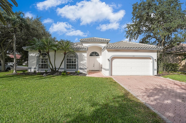 mediterranean / spanish home featuring a front yard and a garage