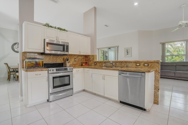 kitchen with white cabinetry, kitchen peninsula, stainless steel appliances, and light tile patterned floors