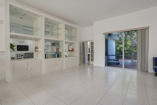 unfurnished living room with ceiling fan, light tile patterned floors, and built in shelves