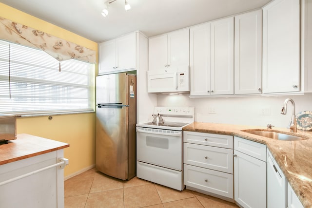 kitchen with white cabinets, sink, light tile patterned floors, and white appliances