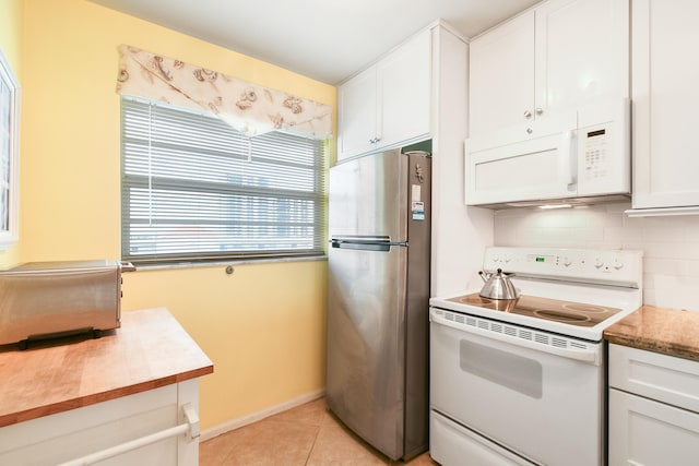 kitchen featuring white appliances, decorative backsplash, light tile patterned flooring, and white cabinets