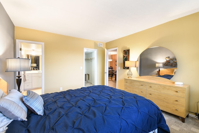 carpeted bedroom featuring a closet, ensuite bath, and a walk in closet