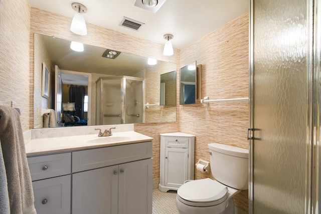 bathroom with a shower with door, tile walls, toilet, vanity, and tile patterned flooring