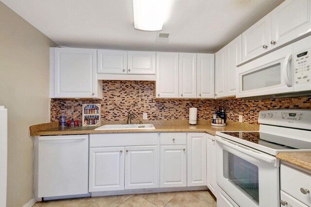 kitchen with white appliances, light tile patterned floors, sink, and white cabinets