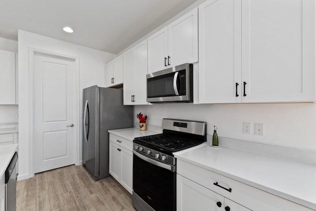 kitchen with appliances with stainless steel finishes, light hardwood / wood-style flooring, and white cabinetry