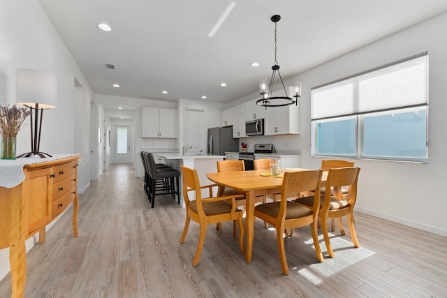 dining space featuring light hardwood / wood-style floors, sink, and a chandelier