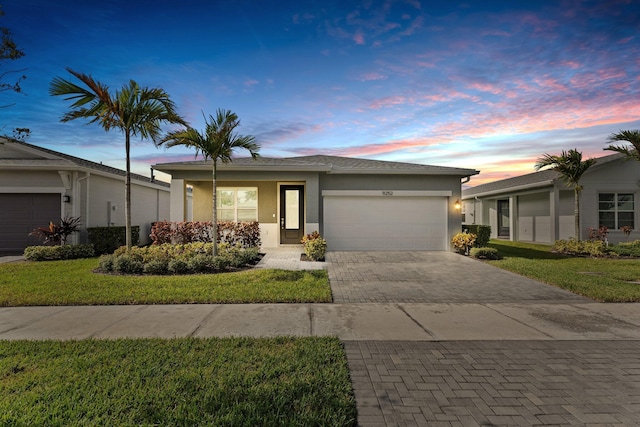 ranch-style home featuring a garage and a lawn