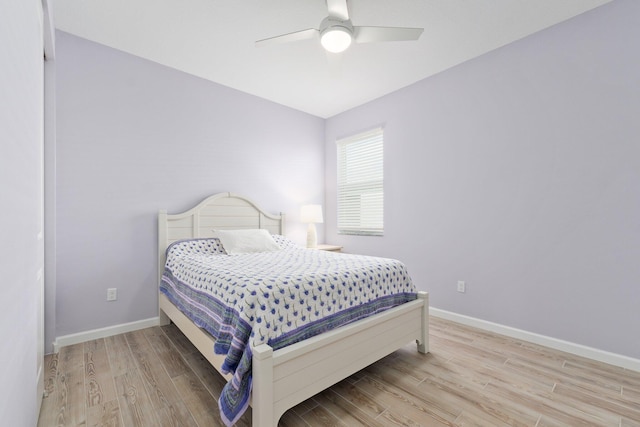 bedroom with light hardwood / wood-style flooring, vaulted ceiling, and ceiling fan