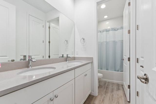 full bathroom with toilet, hardwood / wood-style floors, shower / tub combo with curtain, and vanity