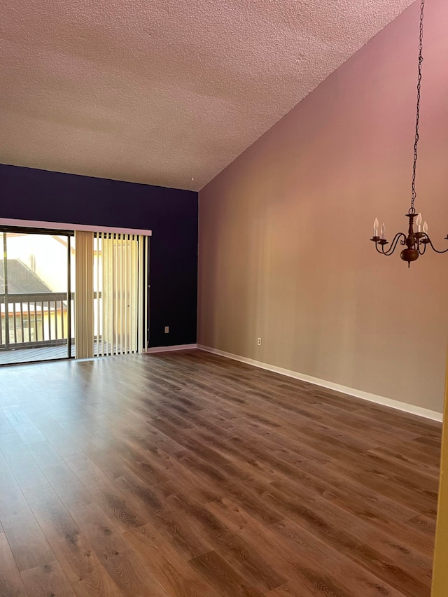 spare room with an inviting chandelier, a textured ceiling, and dark hardwood / wood-style flooring