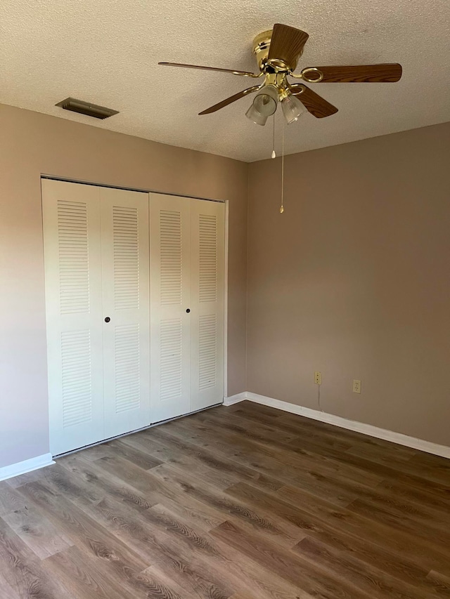 unfurnished bedroom with a textured ceiling, wood-type flooring, and ceiling fan