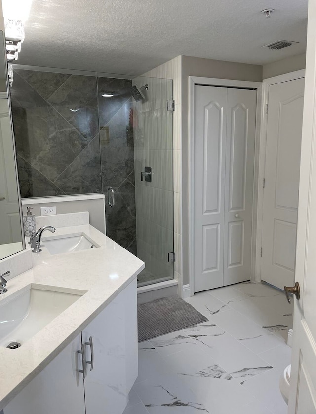 bathroom with vanity, a textured ceiling, and walk in shower