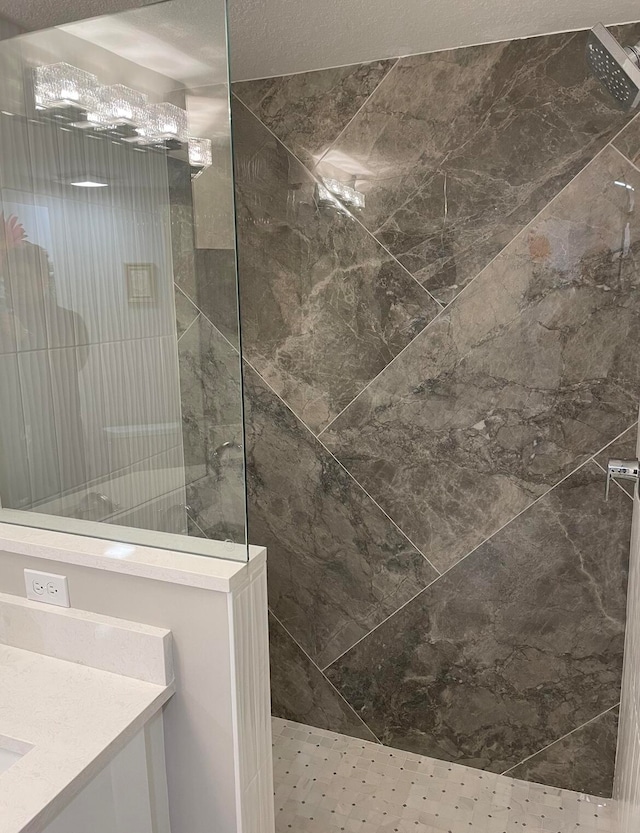 bathroom with vanity, tiled shower, and a textured ceiling