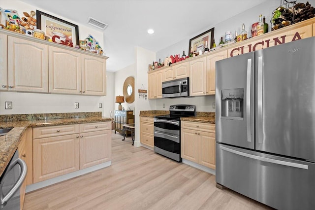 kitchen featuring light hardwood / wood-style floors, stainless steel appliances, and dark stone counters