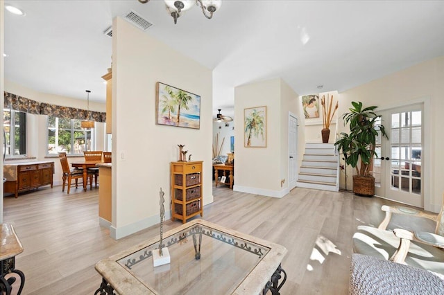 living room featuring light hardwood / wood-style flooring and ceiling fan with notable chandelier