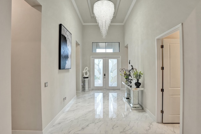 foyer entrance with french doors, crown molding, a towering ceiling, and an inviting chandelier