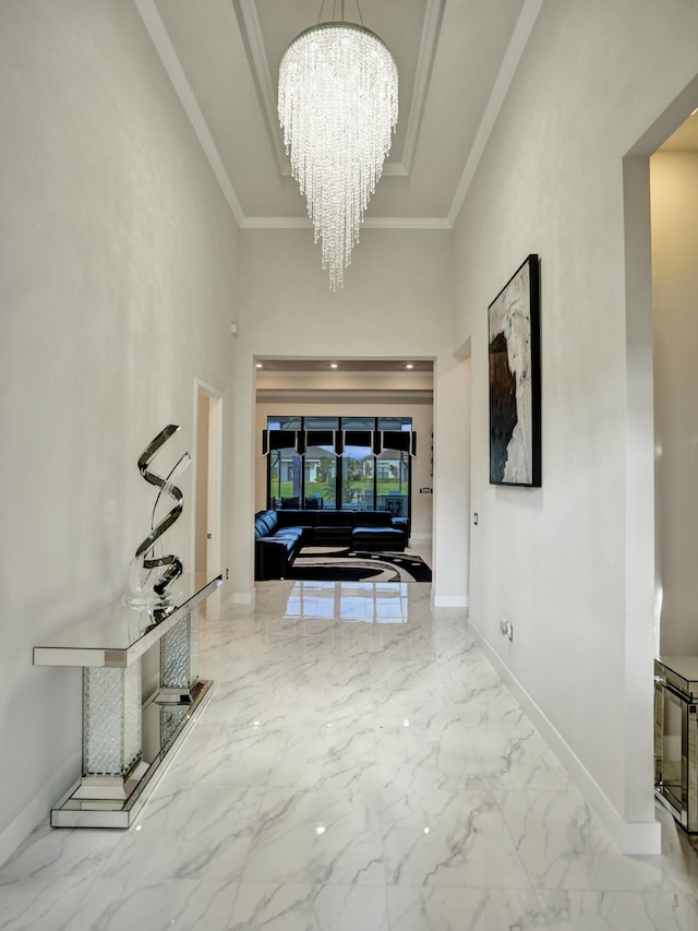 corridor with an inviting chandelier, a high ceiling, and crown molding