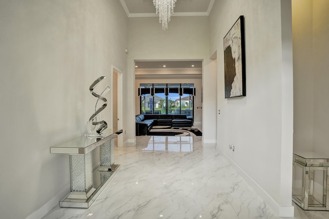 hallway with a towering ceiling, an inviting chandelier, and ornamental molding