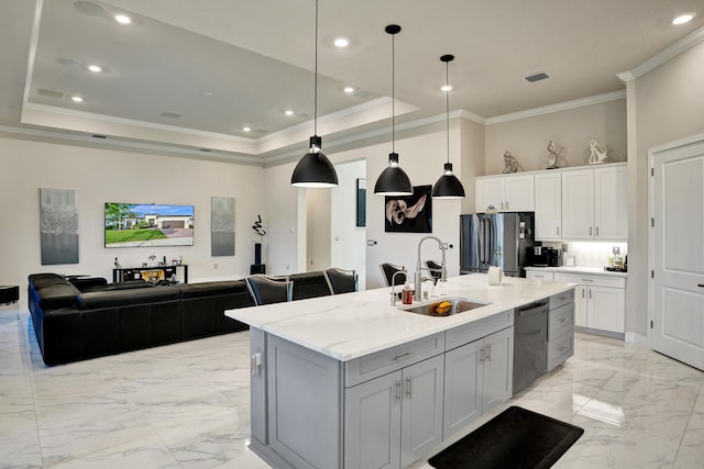 kitchen with appliances with stainless steel finishes, sink, an island with sink, white cabinetry, and light stone counters