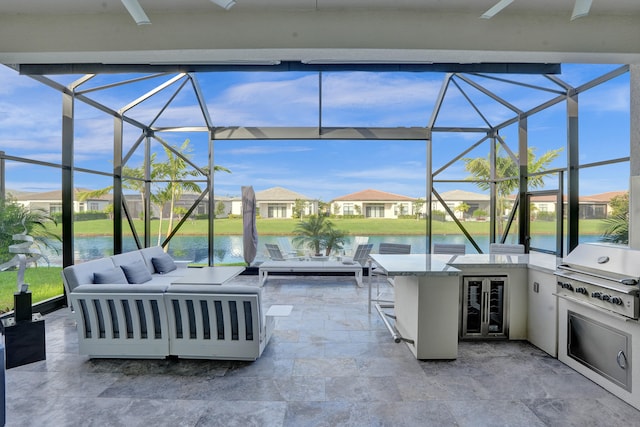 view of patio with a water view, area for grilling, glass enclosure, and an outdoor kitchen