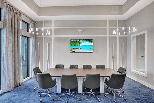 dining space featuring dark carpet, plenty of natural light, and a raised ceiling