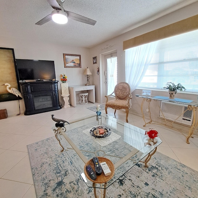 living room with tile patterned flooring, ceiling fan, a wall mounted air conditioner, and a textured ceiling