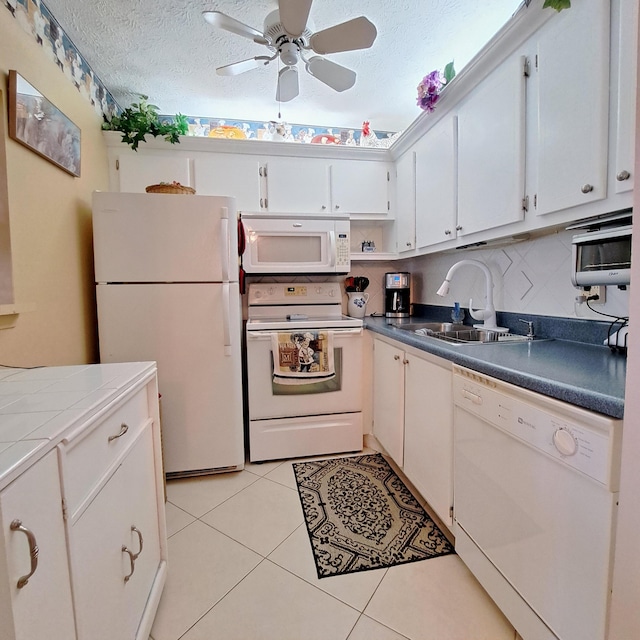 kitchen with sink, white appliances, white cabinetry, a textured ceiling, and light tile patterned flooring