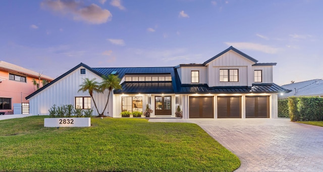 modern farmhouse with a lawn and a garage