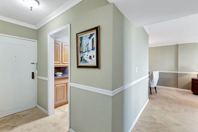 hall with light tile patterned flooring, a textured ceiling, and ornamental molding