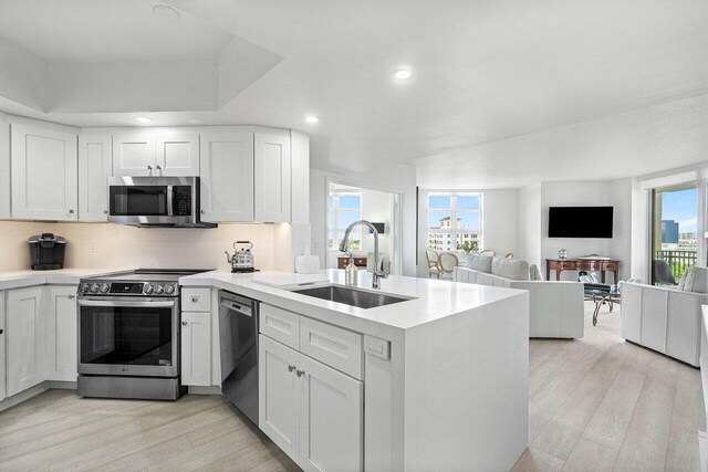 kitchen with a wealth of natural light, sink, kitchen peninsula, and stainless steel appliances