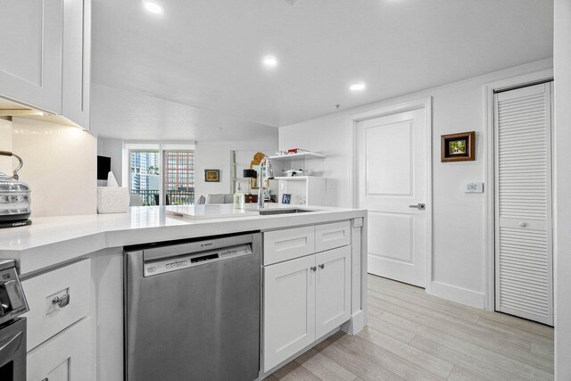 kitchen featuring white cabinetry, dishwasher, light wood-type flooring, and sink