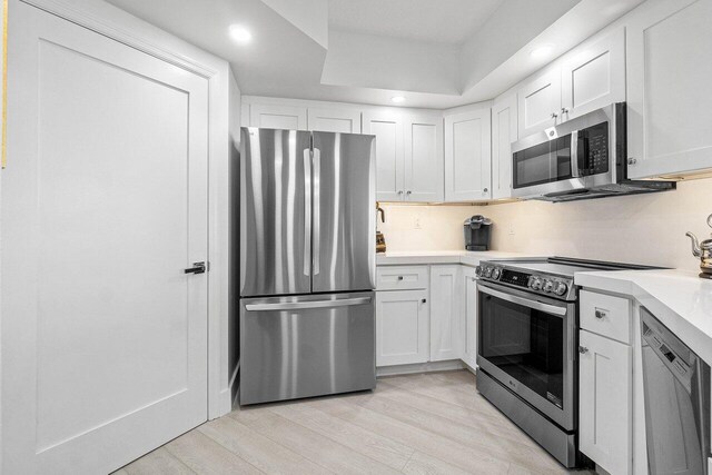 kitchen featuring appliances with stainless steel finishes, light hardwood / wood-style flooring, and white cabinetry