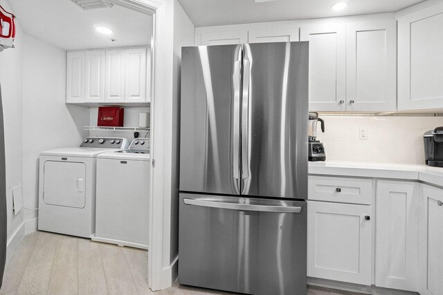 clothes washing area featuring independent washer and dryer and light wood-type flooring