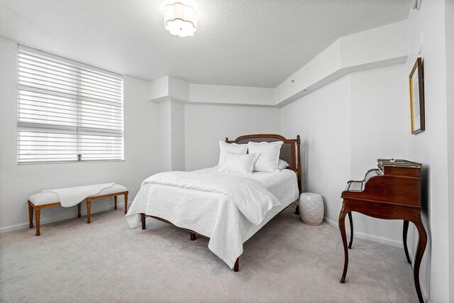 bedroom featuring light carpet and a textured ceiling