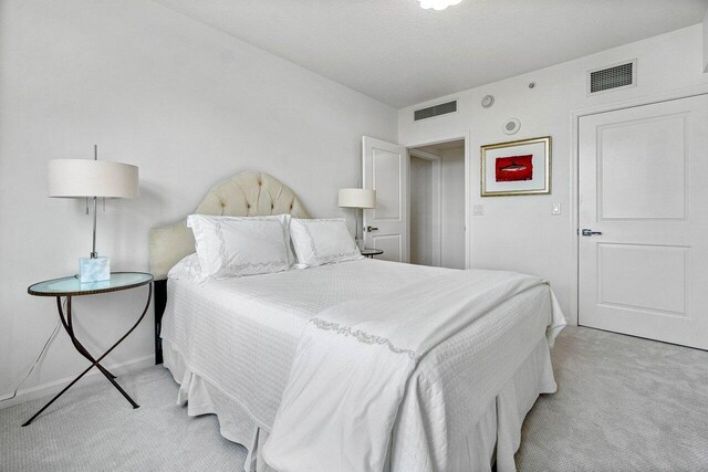 bedroom with light carpet and a textured ceiling