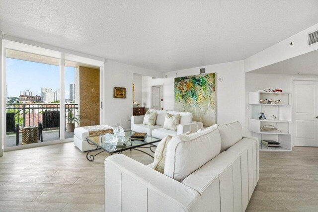 living room with light hardwood / wood-style flooring, a textured ceiling, and floor to ceiling windows