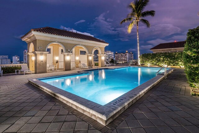 pool at dusk featuring a patio