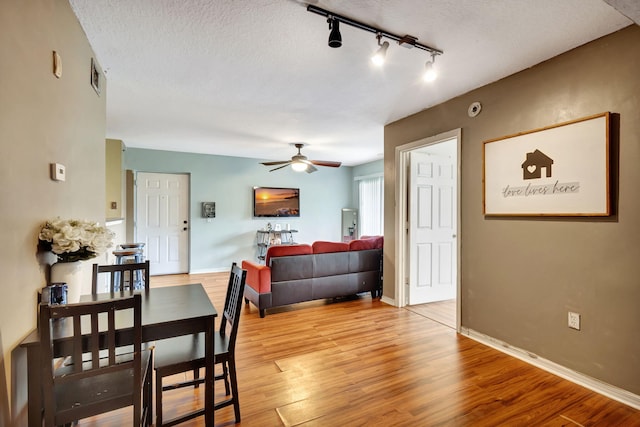 dining space with light hardwood / wood-style floors, a textured ceiling, track lighting, and ceiling fan