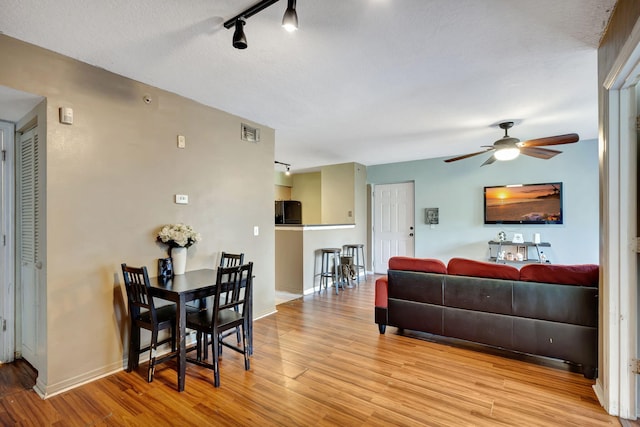 living room featuring light hardwood / wood-style floors, a textured ceiling, and ceiling fan