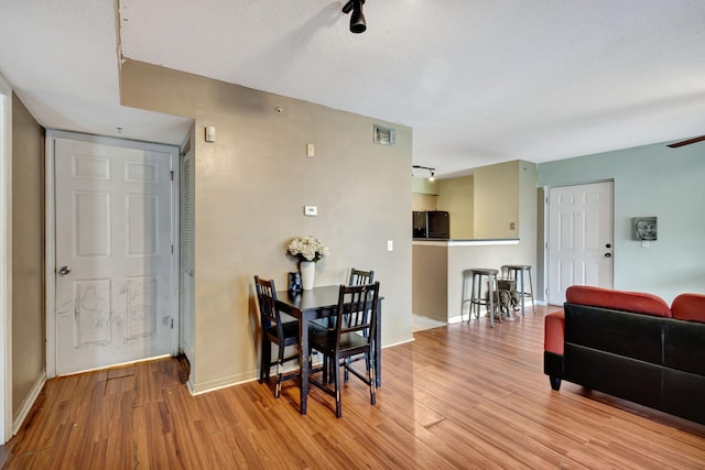 dining room featuring a textured ceiling and light hardwood / wood-style flooring