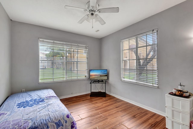 bedroom with multiple windows, wood-type flooring, and ceiling fan